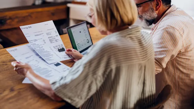 Senior couple carefully reviewing their household energy bill together on a laptop at home.