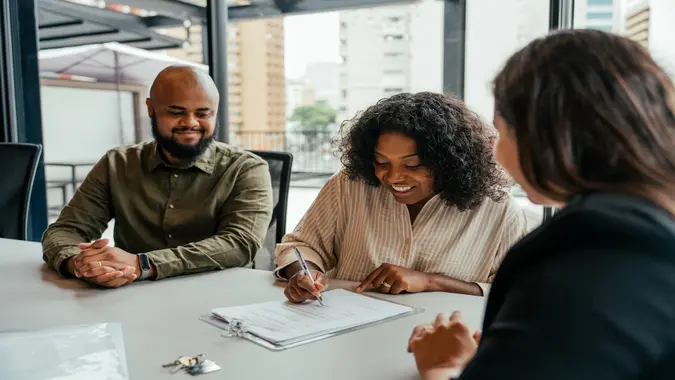 Couple closing real estate contract with real estate agent.