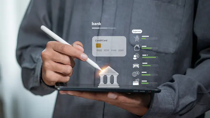 Businessman using stylus on tablet with digital banking and credit card icon, symbolizing financial management, online payment, and fintech innovation.