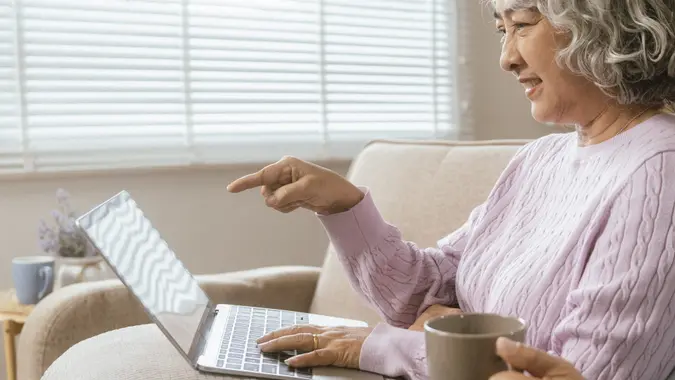 senior couple and documents with laptop for finance, budget planning or retirement annuity on sofa.