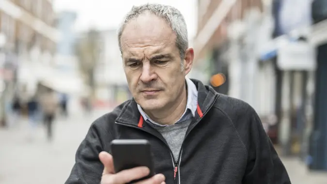 Mature man frowning with smart phone device problems stock photo