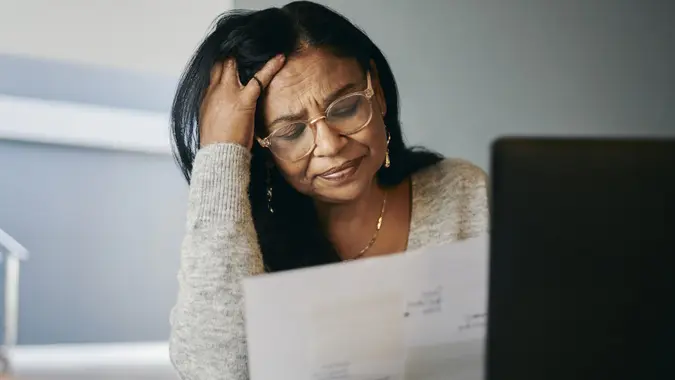 Stressed Mature Woman Managing Pension at Desk, Looking Worried stock photo