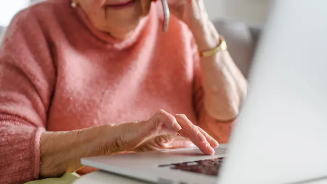 Online and phone scams targeting seniors. Scammer sending email to elderly woman, asking for money, demanding personal, sensitive informations without verification. stock photo