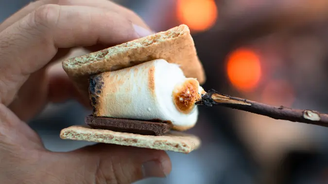 Closeup of person roasting marshmallow enjoying s'more by a campfire. Camping concept. stock photo