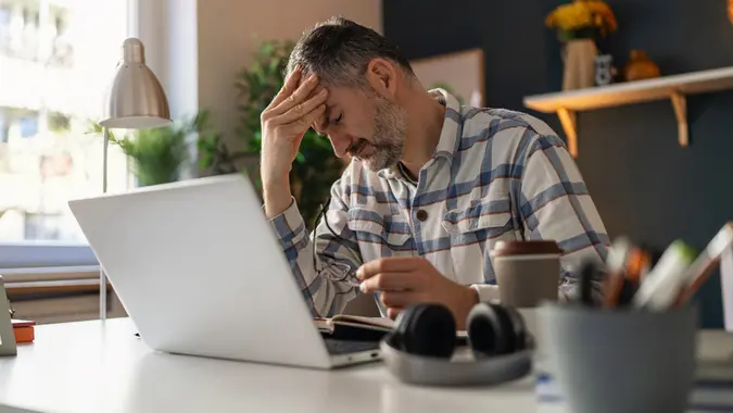 Exhausted and upset mature businessman having problems at work stock photo