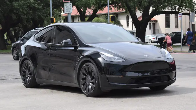 A portrait of a black Tesla Model Y cruising in a downtown district in moderate traffic. stock photo
