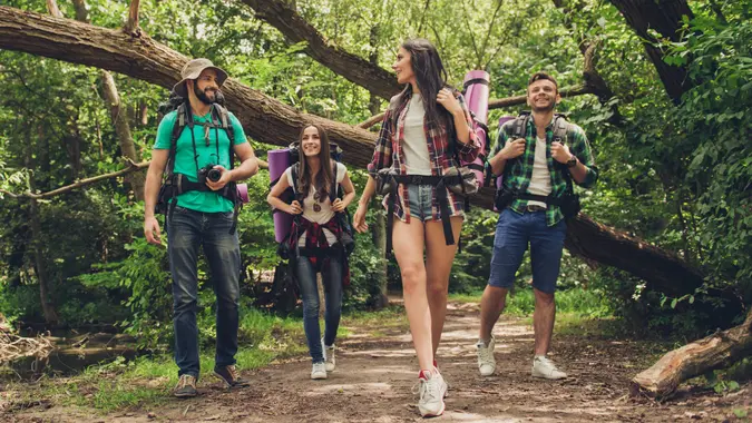 Trekking, camping and wild life concept. Two couples of friends are walking in the sunny spring woods, talking and laughing, all are excited and anxious, jungle trails stock photo