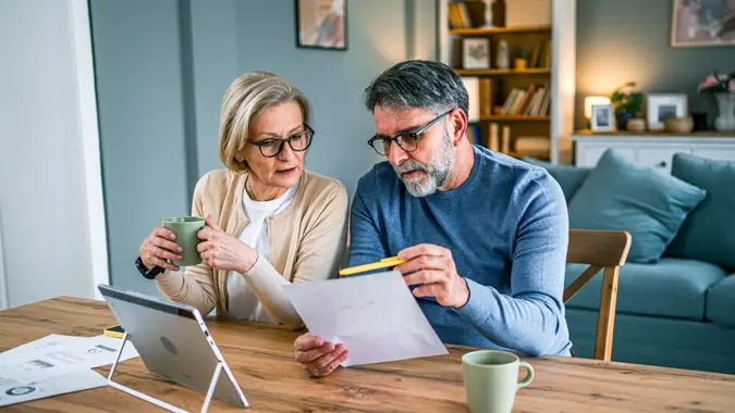 Mature couple using AI to plan for retirement together at home.