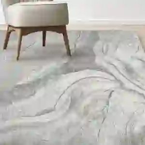 Costco Icon Area Rug Collection, Atoll pictured unrolled with a matching chair in the top left corner.
