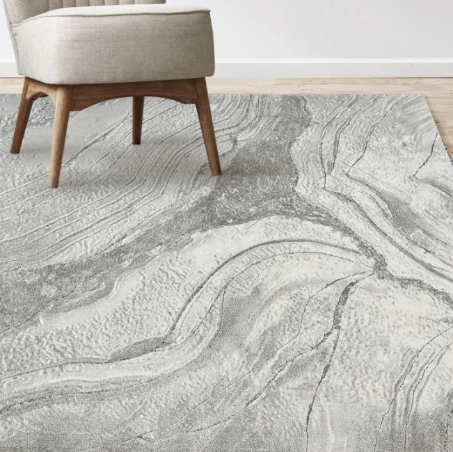Costco Icon Area Rug Collection, Atoll pictured unrolled with a matching chair in the top left corner.
