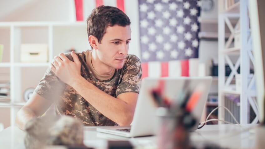 Young soldier man using a computer into his office.