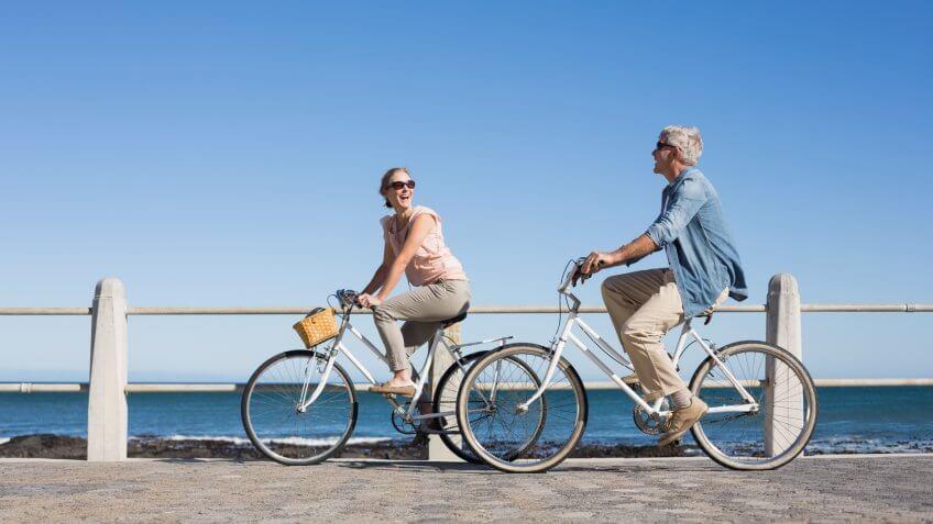 Happy casual couple going for a bike ride on the pier on a sunny day.