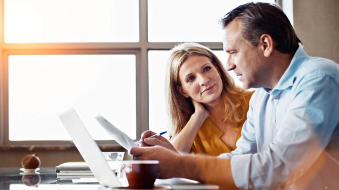 Shot of a mature couple sitting at their dining room table doing online banking using a laptop.