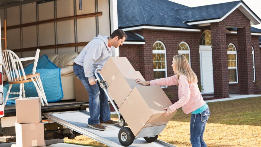 Mid adult couple (30s) unloading moving van.