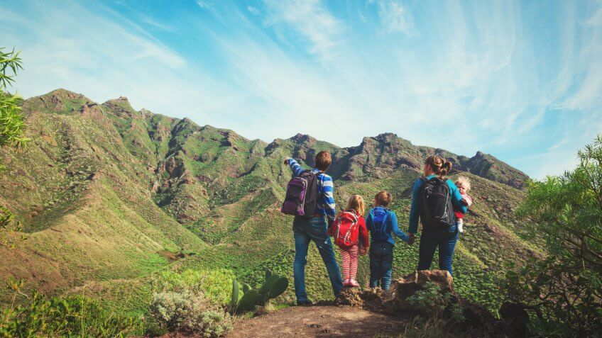 family with three kids hiking in mountains.