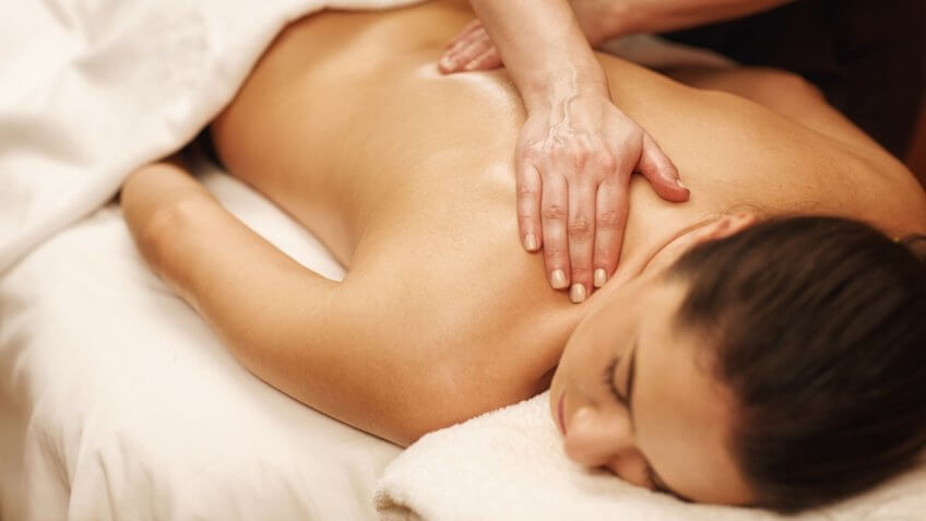 Young woman receiving back massage at spa salon.