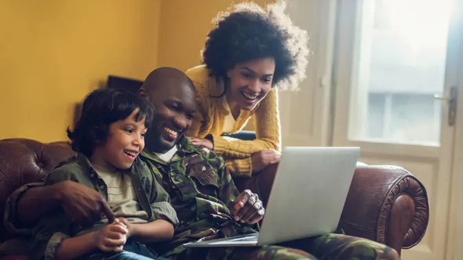 Happy military family relaxing at home and using computer together.