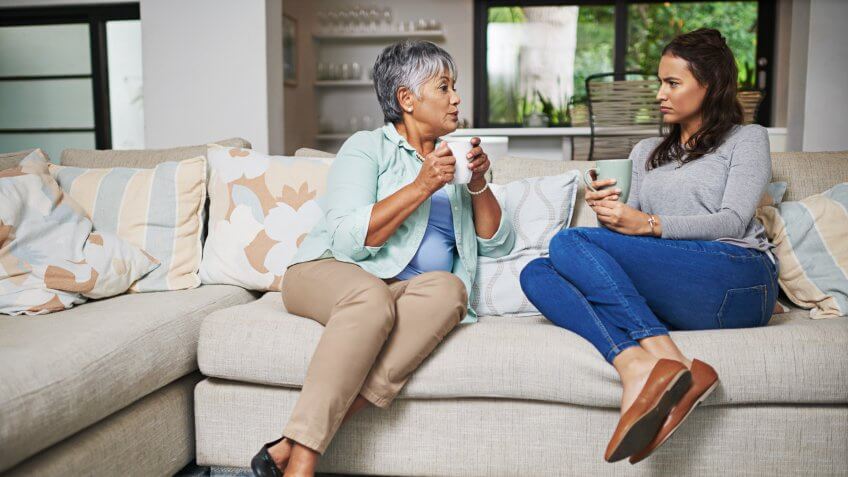 Shot of a young woman and her mother catching up on the sofa while drinking coffee.