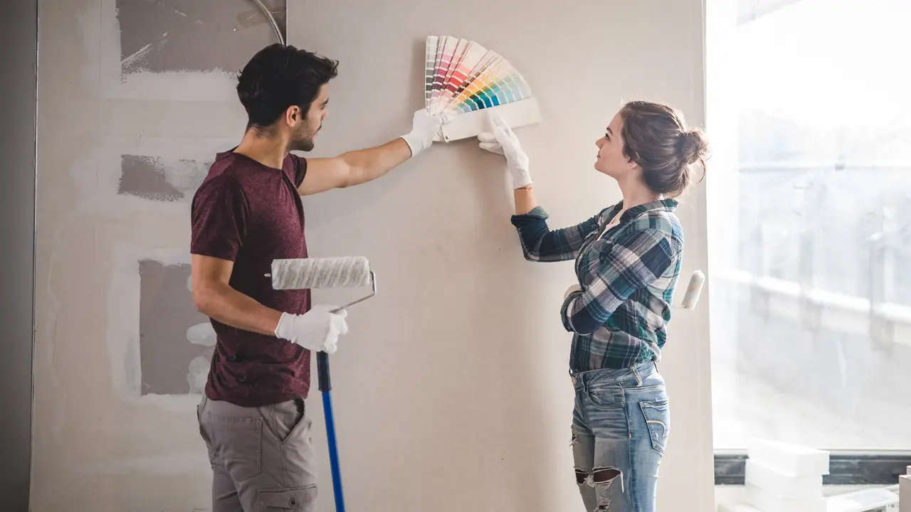 Young couple choosing the right color for their wall in new apartment.