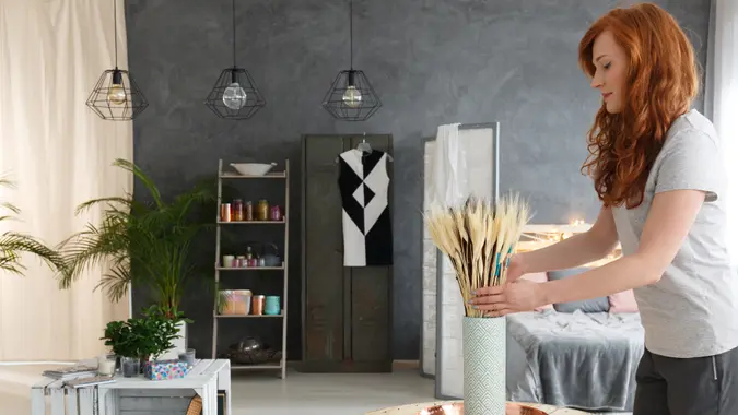 Young woman with red hair decorating contemporary fancy industrial apartment.