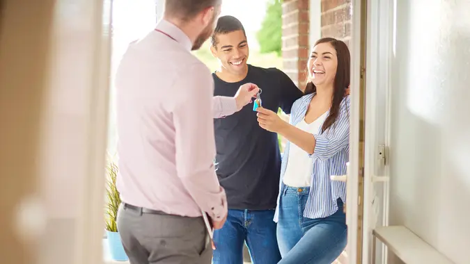 a young couple view a property guided by an estate agent.
