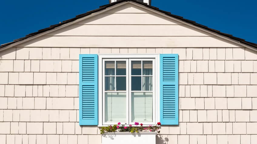 white wooden facade with blue shutters and flowers