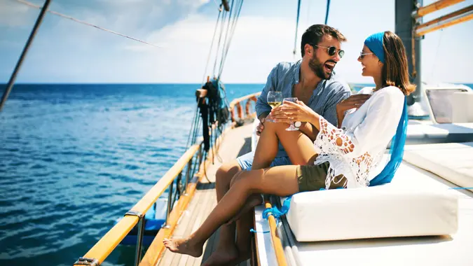 Closeup side view of a young couple relaxing on a sailboat cruise while sailing close to the coast.