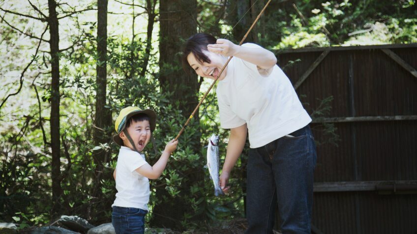 An asian mother helping her son fishing.