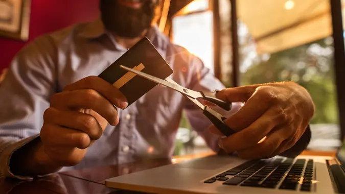 Hands of a businessman using scissors and cutting his credit card.