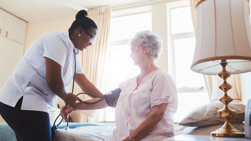 Female nurse doing blood pressure measurement of a senior woman patient.