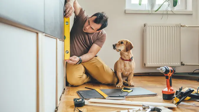 Man doing renovation work at home together with his small yellow dog.