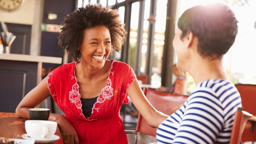 Two female friends talking at a coffee shop.
