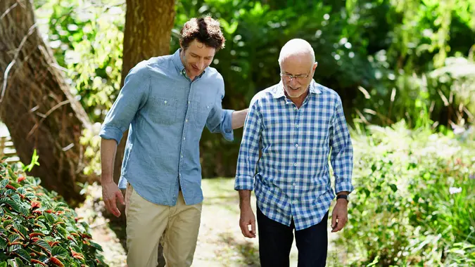Happy senior man and son walking together in park.