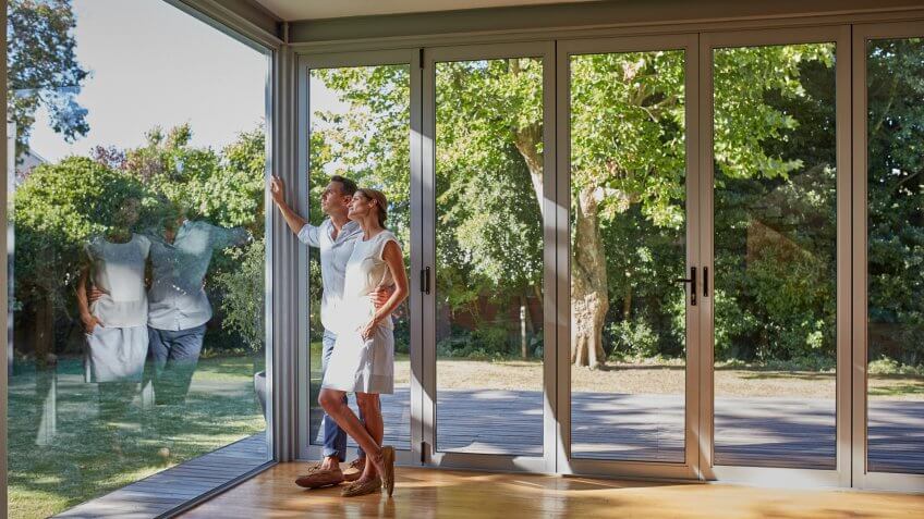 Full length of loving mid adult couple looking through glass window.