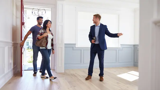 Realtor Showing Hispanic Couple Around New Home.