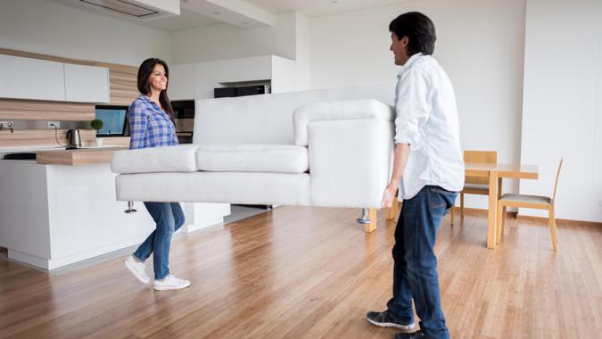 Happy Latin American couple moving home and carrying furniture.