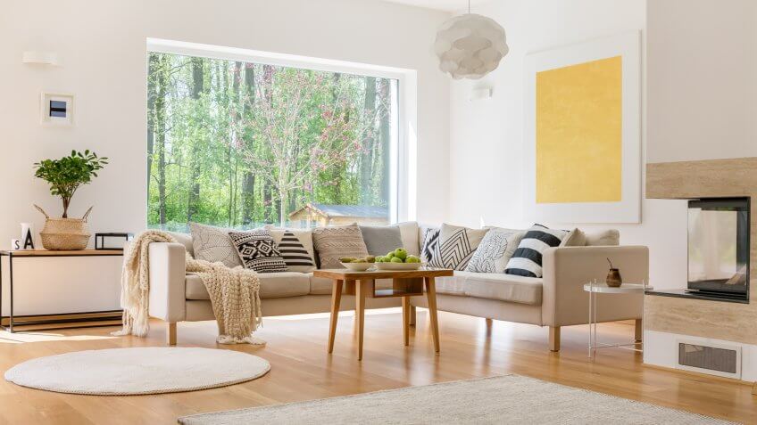 White comfortable sofa with blanket and pillows in modern lounge.