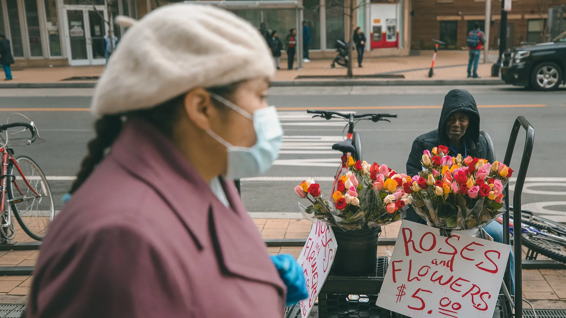 A street vendor sells flowers as a mask-wearing shopper walks in the Columbia Heights area in Washington, DC, USA, 19 March 2020.
