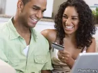 Black couple holding a laptop and credit card