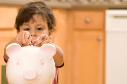 Child putting change into a piggy bank