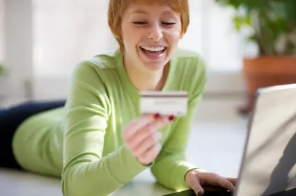 Smiling young woman shopping online with credit card and laptop