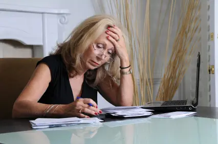 Stressed woman overlooking her stack of papers and laptop
